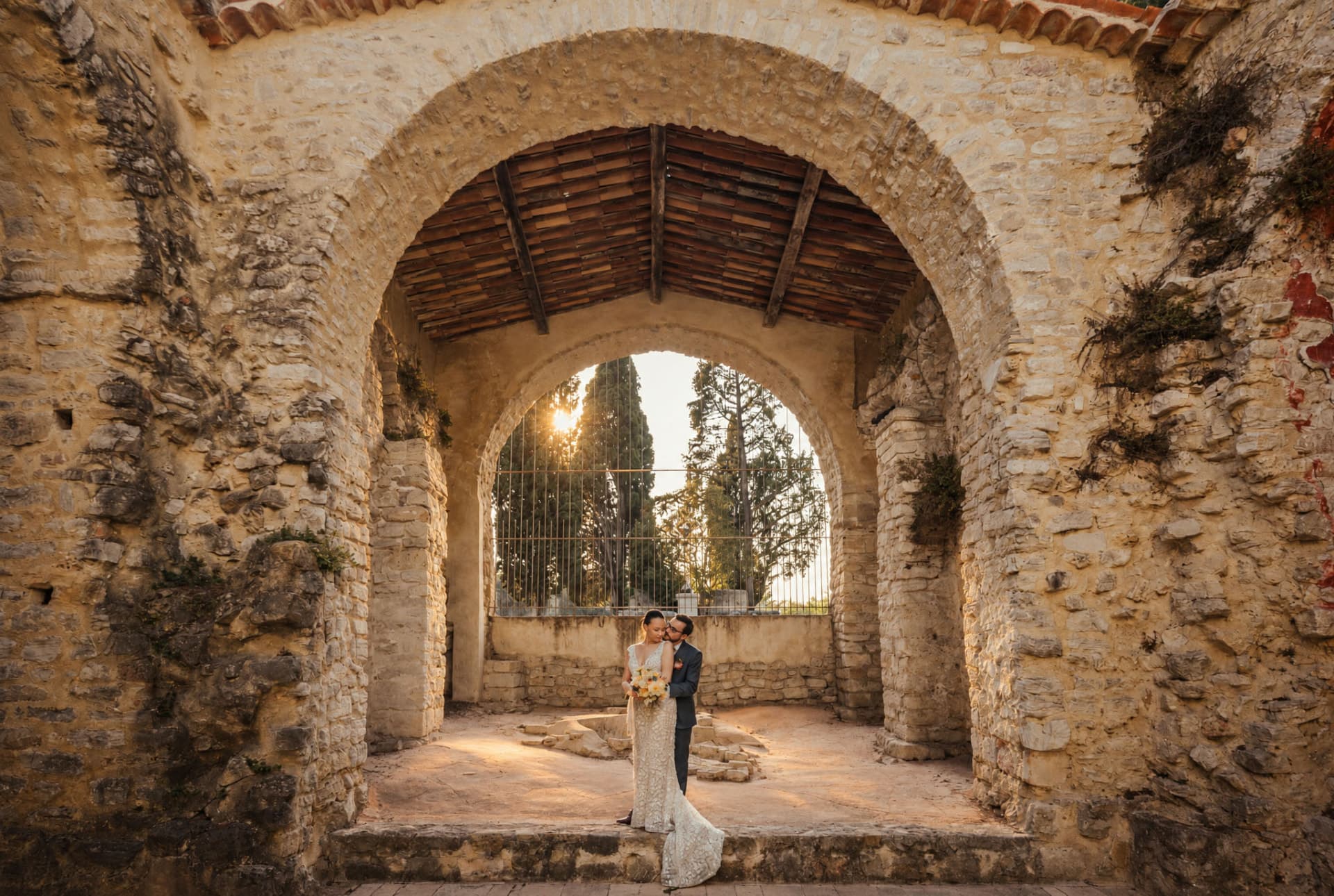 Couple under the great stone arch of an old chapel at sunset